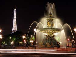 Fotografía nocturna de una fuente de París con la Torre Eiffel de fondo